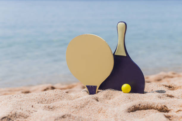 Set for a game of beach tennis, close-up Wooden rackets and yellow ball in the sand on the beach paddle ball stock pictures, royalty-free photos & images