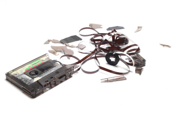 This shows a well known problem with the old fashioned compact cassettes: the tape used to come out, making the cassette useless. Vintage compact cassette tape on white background.