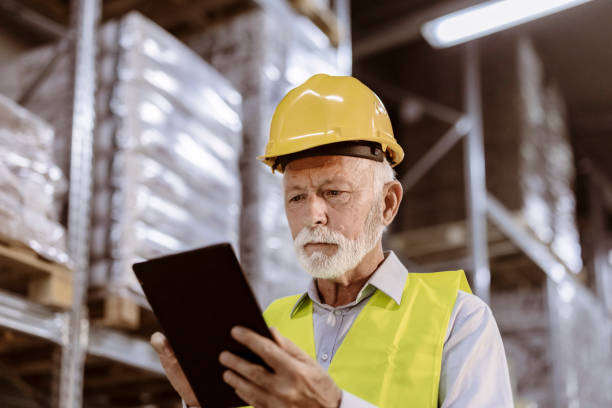 istock Senior Male Warehouse Worker with Tablet Pc Computer Checking Goods at Warehouse 1385975562