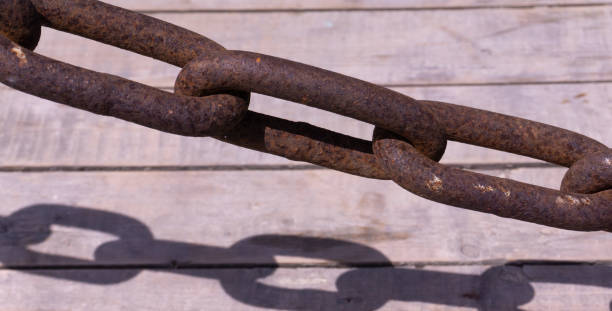 istock Old rusty chain on the wooden pier with sandy beach 1385981077