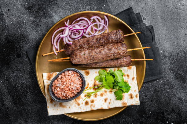 istock Lamb meat kofta kebab, onion and flat bread on plate. Black background. Top view 1385983285