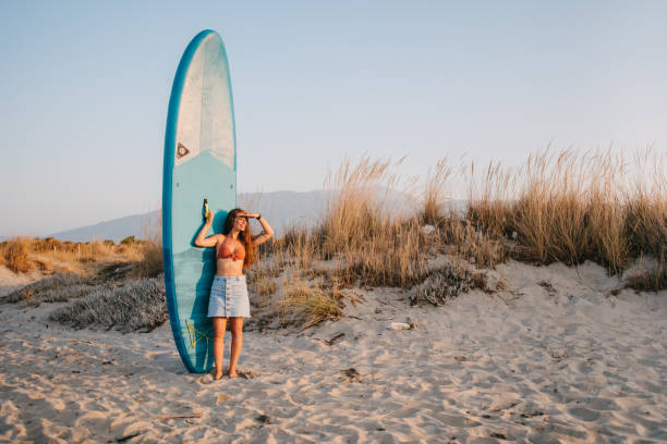 istock Woman standing next to a paddleboard and looking into distance 1385983579