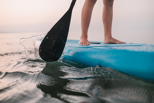 Oar of paddle boarder over a calm water