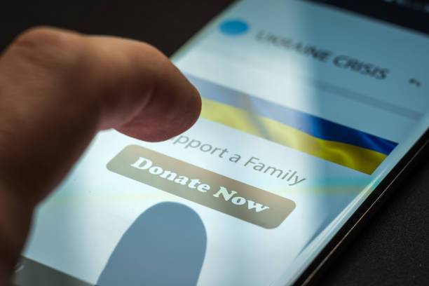 istock Close-up finger pressing donate button on smartphone screen. Donation money online concept 1385983905
