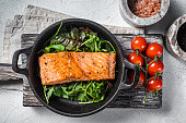 Salmon fillets, grilled steaks in skillet with herbs. White background. Top view