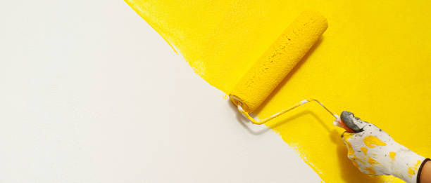 istock Painter is painting the interior wall yellow 1385985480