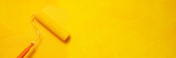 istock Painter is painting the interior wall yellow 1385985505