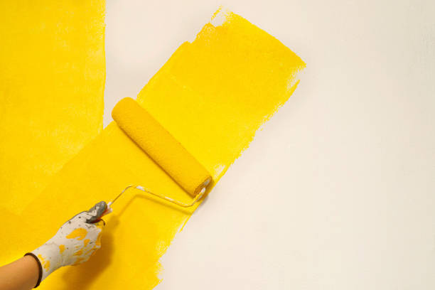 istock Painter is painting the interior wall yellow 1385985506