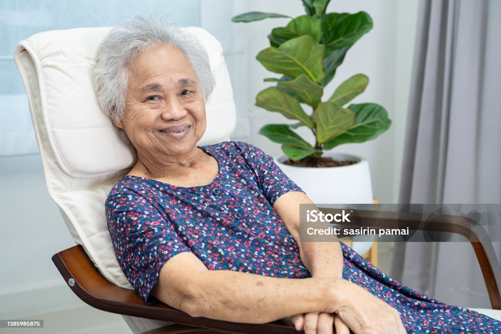 Asian elderly woman sitting and relaxing with happy in rocking chair at room in home. Senior Adult Stock Photo