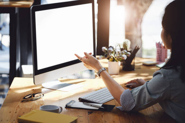istock A woman pointing at a computer with a blank white screen. The blank space on the white screen can be used to write a message or place an image. 1385988432