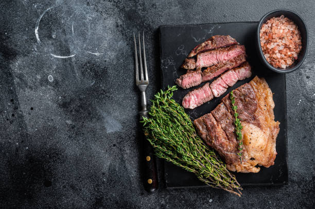 istock Roasted bbq Chuck Roll beef steaks with herbs. Black background. Top view. Copy space 1385988634