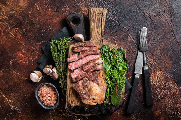 istock Grilled Chuck Roll beef steak with salad on wooden board. Dark background. Top view 1385990575