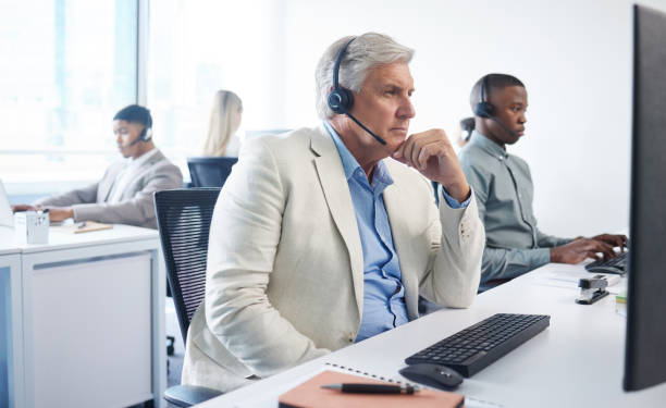 istock Portrait of a mature businessman using a headset and computer in a modern office 1386003154
