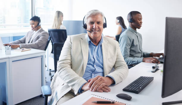 istock Portrait of a mature businessman using a headset and computer in a modern office 1386003162