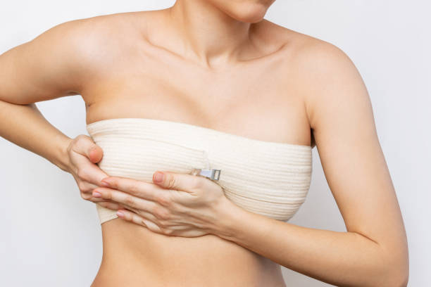 Cropped shot of young woman with elastic bandage after breast augmentation with silicone implants Cropped shot of young woman with elastic bandage after breast augmentation with silicone implants isolated on white background.The result of lifting. Breast size correction. Pain after plastic surgery breast stock pictures, royalty-free photos & images
