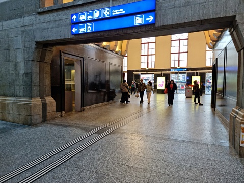 Biel/Bienne railway station serves the bilingual municipality of Biel/Bienne, in the canton of Bern, Switzerland. The building was realized in 1923. The image shows the main hall with several people getting thir next connections.