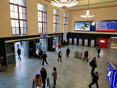 Biel/Bienne railway station serves the bilingual municipality of Biel/Bienne, in the canton of Bern, Switzerland. The building was realized in 1923. The image shows the main hall with several people getting thir next connections.