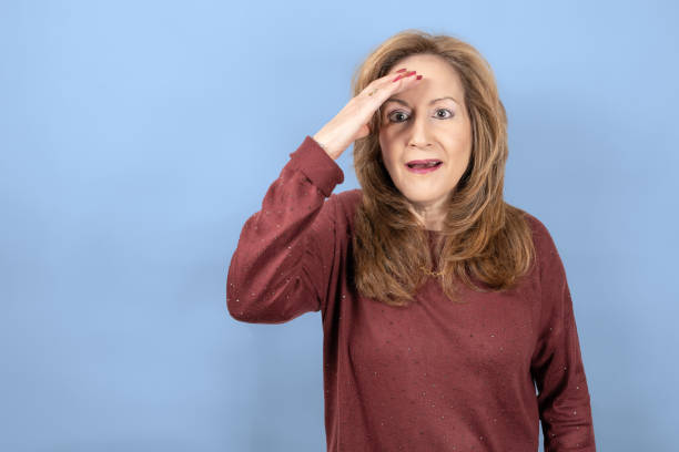 istock Woman with a surprised face and hand on the forehead for emotion, blue studio background. 1386009848