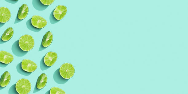 istock Citrus lime fruit as creative background, slices of green lime with hard shadows at sunlight on pastel mint background with copy space. Fruits food concept. Top view, monochrome colored 1386010061