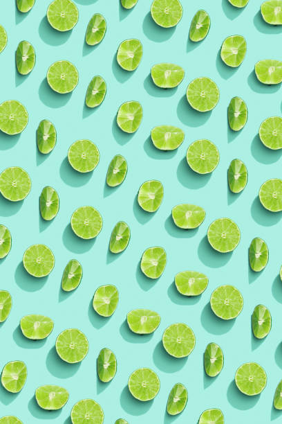 istock Lime fruit as bring summer food pattern, slices of green citrus with hard shadows at sunlight on pastel mint background. Healthy fruits food concept.  Monochrome flat lay with juicy lime 1386010068