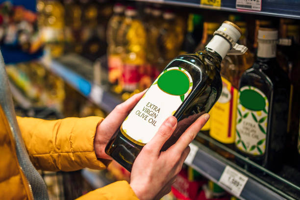 Woman buying olive oil Woman buying olive oil from supermarket.. She's choosing from the shelf olive oil photos stock pictures, royalty-free photos & images