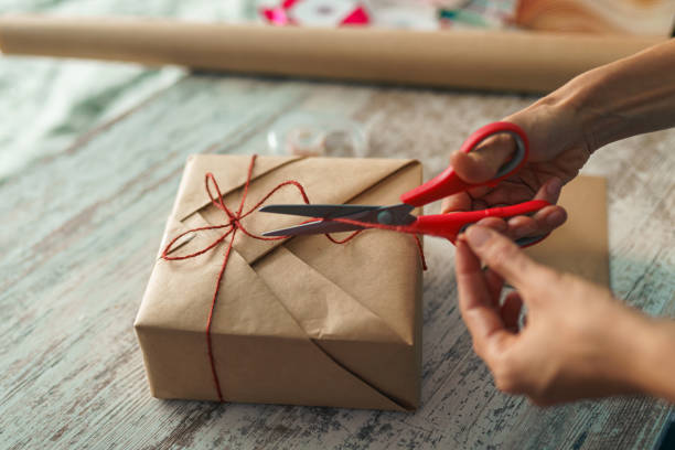 Woman packaging box with kraft wrapping paper and natural twine stock photo