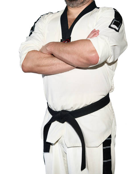 Man in taekwondo martial arts uniform fold one's arms isolated on the white background. Black belt