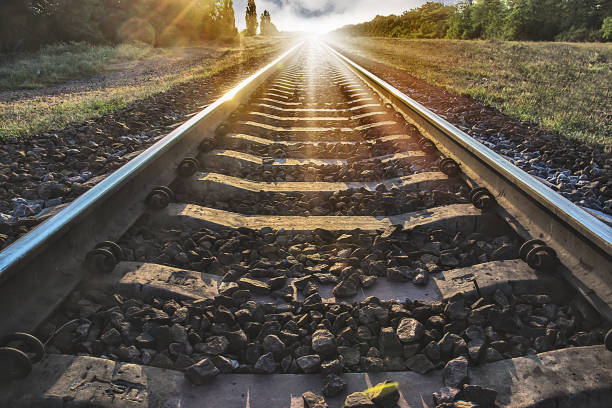 os trilhos saem para a distância contra o fundo do pôr do sol - railroad track - fotografias e filmes do acervo