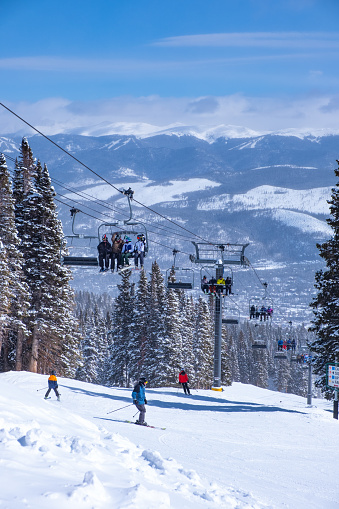 Skiers ski as the lift carries more skiers up the mountain in Breckenridge, Colorado, March 11, 2022.