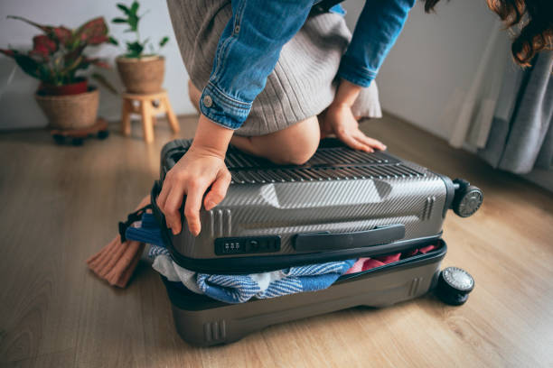 istock A woman struggling to fit everything into her case. 1386031042