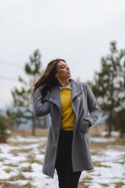 vertikales porträt einer jungen frau in einer nicht-städtischen umgebung mit etwas schnee auf dem boden - non urban scene nature rural scene outdoors stock-fotos und bilder