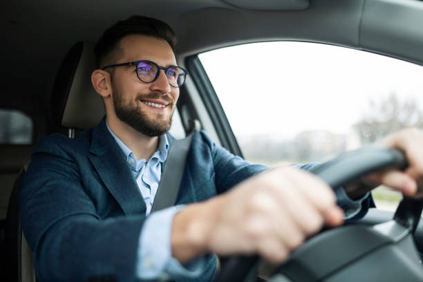 sonriente hombre de negocios conduciendo su coche - conducir fotografías e imágenes de stock