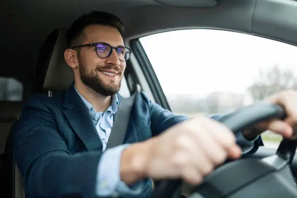 Photo of Smiling businessman driving his car
