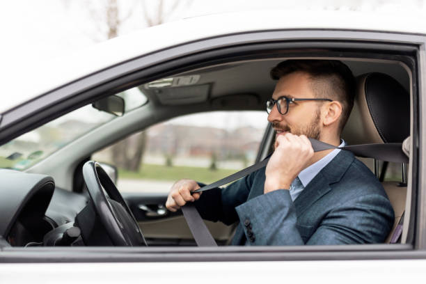 бизнесмен пристегивается ремнем безопасности - seat belt safety protection driving стоковые фото и изображения