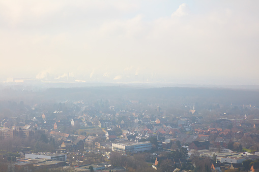 The Ruhr area with houses, factories and forest in the fog.