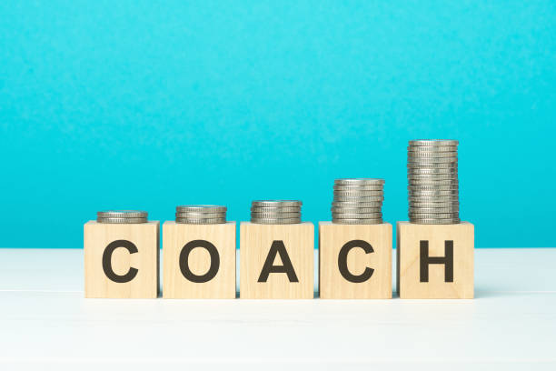 istock wooden blocks with text Coach and coins on wooden table. copy space. blue background 1386041133