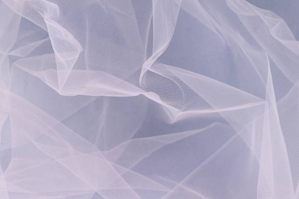 istock sheer tulle fabric arranged in soft folds on a blue background, selective focus 1386043775