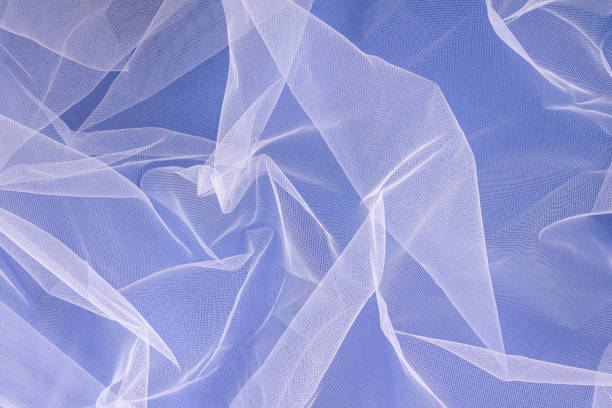 istock sheer tulle fabric arranged in soft folds on a blue background, selective focus 1386043985