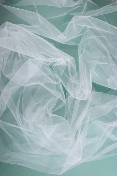 istock transparent tulle fabric arranged in soft folds on a green background, selective focus 1386044339