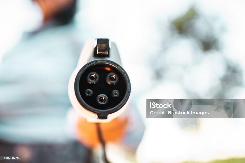 Human hand is holding electric car charging connect to electric car Car Stock Photo