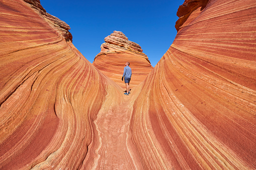 Hiker exploring the famous Wave of Coyote Buttes North in the Paria Canyon-Vermilion Cliffs Wilderness of the Colorado Plateau in southern Utah and northern Arizona USA.