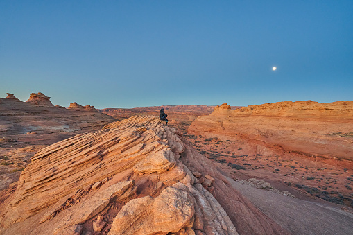 Hiker takes in the sunrise Over Unique Rock Formations of Glen Canyon National Recreation Area in Page Arizona  USA
