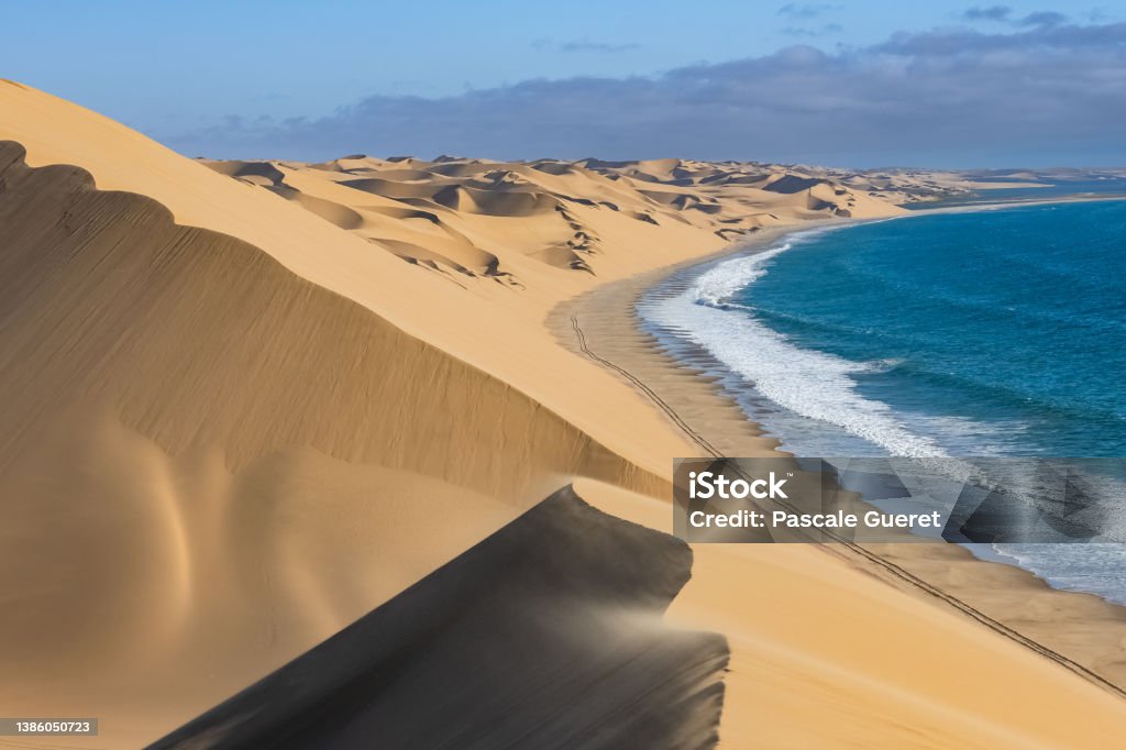 Namibia, the Namib desert, landscape Namibia, the Namib desert, landscape of yellow dunes falling into the sea, the wind blowing on the sand Skeleton Coast Stock Photo