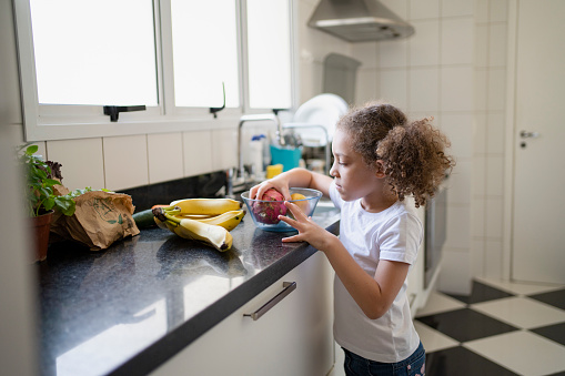 Little girl choosing fruit in the kitchen at home