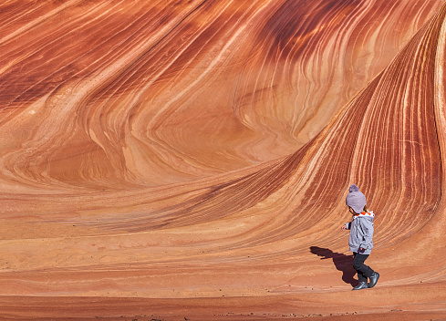Toddler Girl exploring the famous Wave of Coyote Buttes North in the Paria Canyon-Vermilion Cliffs Wilderness of the Colorado Plateau in southern Utah and northern Arizona USA.