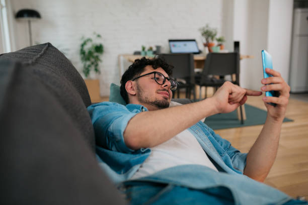 istock Young Caucasian man using a smart phone at home 1386052488