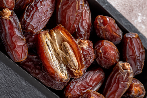 Close-up view of ripe Medina dates pile in a bowl with kernel of date fruit. Inner section view of the date fruit.