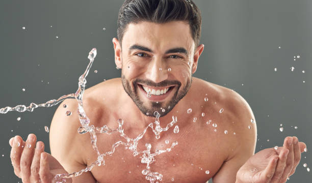 회색 배경에 서있는 동안 그의 얼굴을 씻어 잘 생긴 젊은 완의 샷 - water washing face human face splashing 뉴스 사진 이미지
