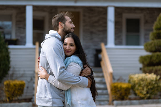 Adult brother and sister hugging in front of their house stock photo