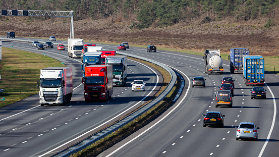 Rijssen, Overijssel, Netherlands, february 23rd 2022, daytime traffic (cars, vans, trucks) driving on the Dutch A1 highway at Rijssen - the A1 is a 157 km long multiple lane highway that crosses the country from West (Amsterdam) to East (Germany)